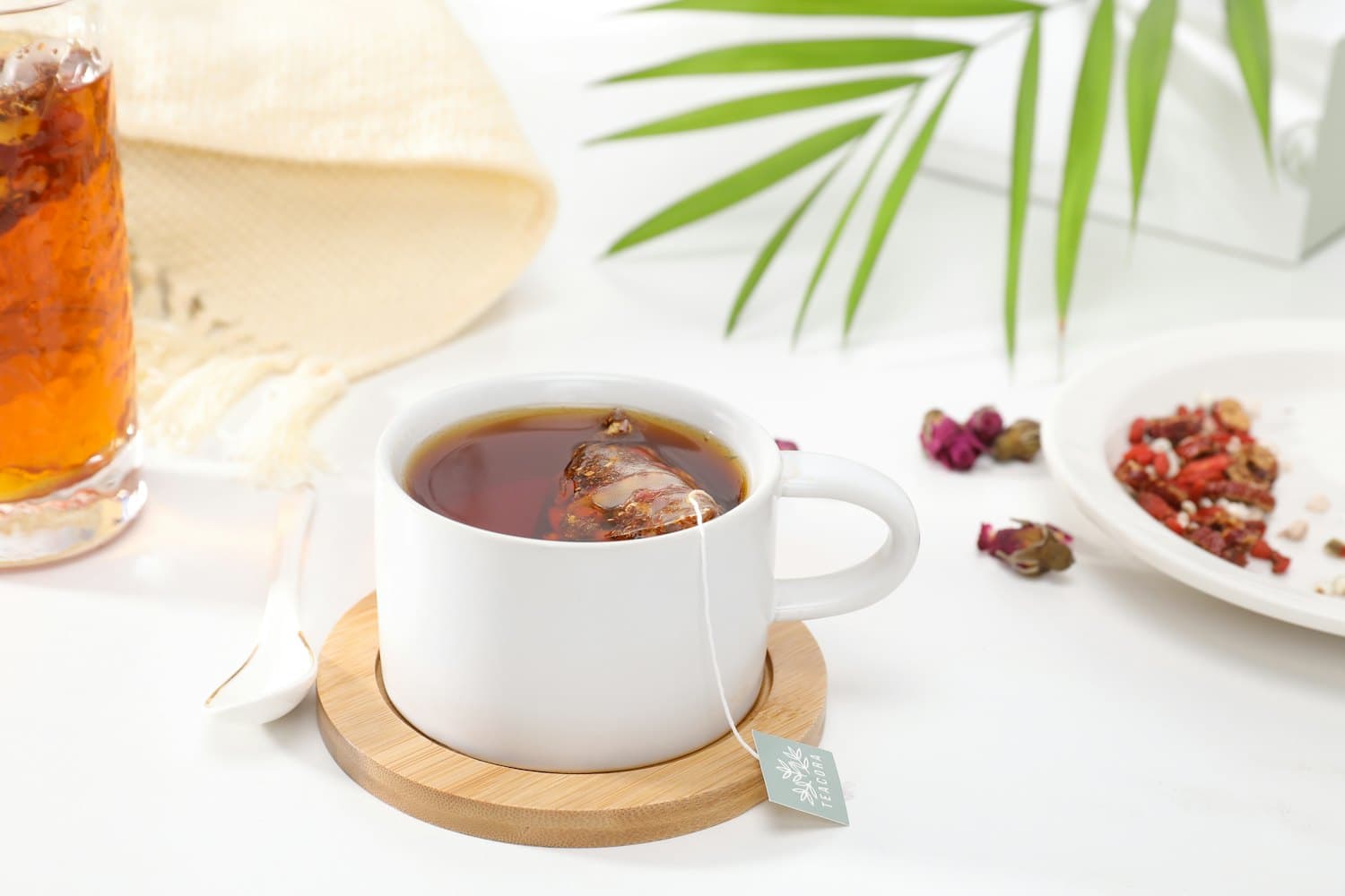 A glass cup of milky tea ringed with loose leaves